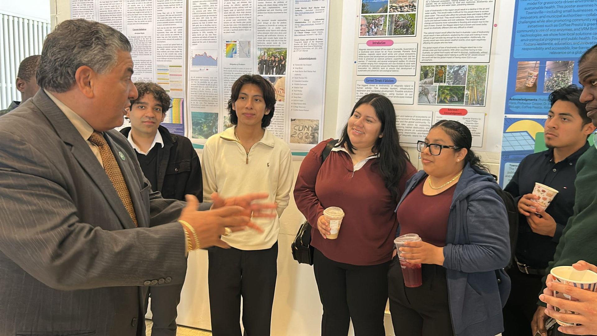 A CUNY faculty member discussing the student research posters with the group